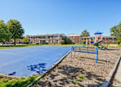 Thumbnail 2 of 4 - A basketball court in a park with a playground in the background.