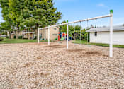 Thumbnail 1 of 5 - A playground with a swing set and a slide.