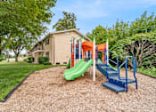 Thumbnail 3 of 5 - A playground with a green slide and a blue staircase.