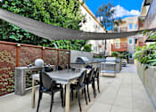 Thumbnail 14 of 41 - A patio with a table and chairs under a shade sail.