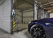 Thumbnail 16 of 41 - A car is parked in a garage next to a gate with a digital display.