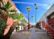 Thumbnail 3 of 8 - A pathway with red railings and palm trees.