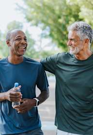 Two men are walking and talking in a park.