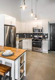 A kitchen with black cabinets and a white door.