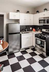 A kitchen with black cabinets and a white door.