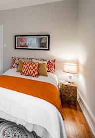 A bedroom with a large bed and two paintings on the wall.