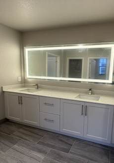 A bathroom with a sink, mirror, and cabinets.
