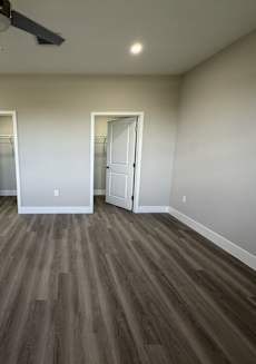 A room with a ceiling fan and wooden flooring.