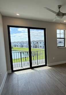 A room with a ceiling fan and sliding glass doors.