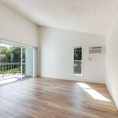 A room with wooden floors and white walls, with a sliding glass door leading to a balcony. at Hill Valley Apartments, Novato
