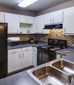 A kitchen with a black refrigerator and white cabinets.