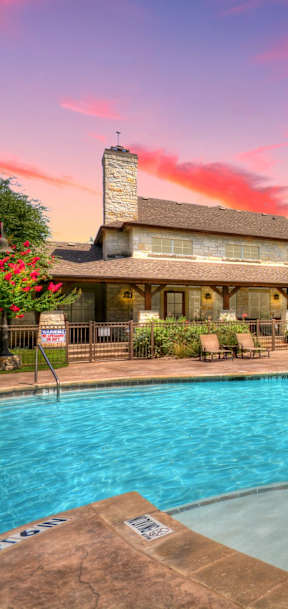 A large swimming pool in front of a building with a sunset in the background.