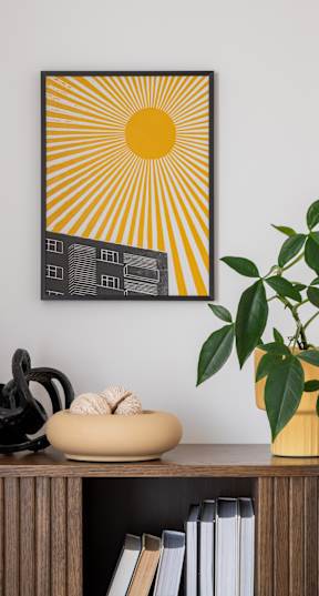 A sunny yellow and black picture hangs on a wall above a shelf with books, sculptures, and a plant at The Laurent at Laurel Apartments, Edmonton, AB, T6T 2T5