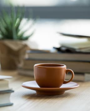 a cup of coffee sitting on a table next to a pile of books at Amity Oak in Amityville, NY 11701