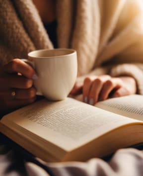 a cup of coffee sitting on a table with books at Platt Gardens, West Babylon, New York