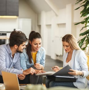 a group of people sitting on a couch looking at a laptop
