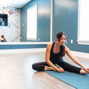 a woman sitting on a yoga mat in a yoga studio