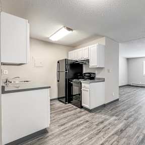 A kitchen with white cabinets and a black refrigerator at The Ridges Apartments, Iowa
