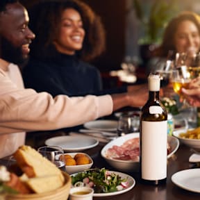A group of people toasting with wine glasses at a dinner table.