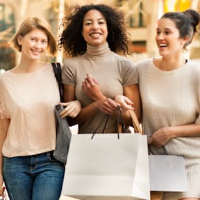 Three women are walking down the street carrying shopping bags.