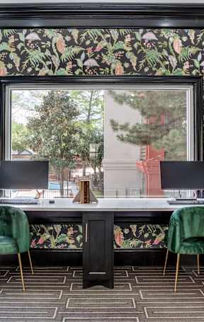A table with four chairs and a potted plant is in front of a window.
