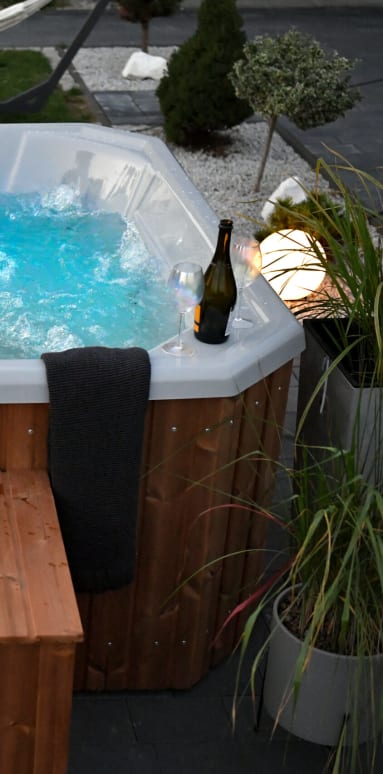 a hot tub with a bench and a bottle of wine