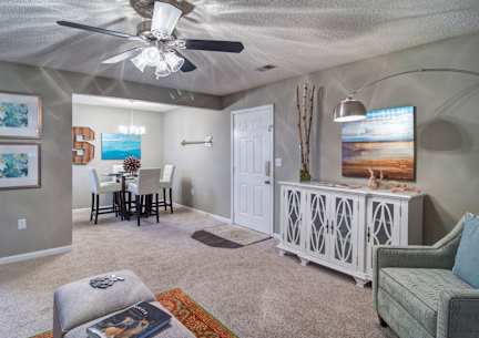 A living room with a grey couch, a white cabinet, and a ceiling fan.