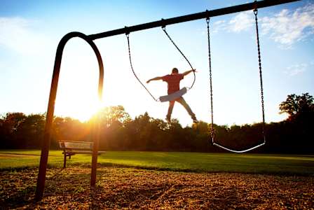 A person is swinging on a swing set in a park.