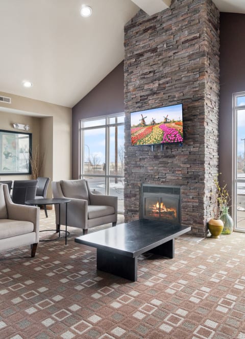 a lobby with couches chairs and a fireplace    and a glass door