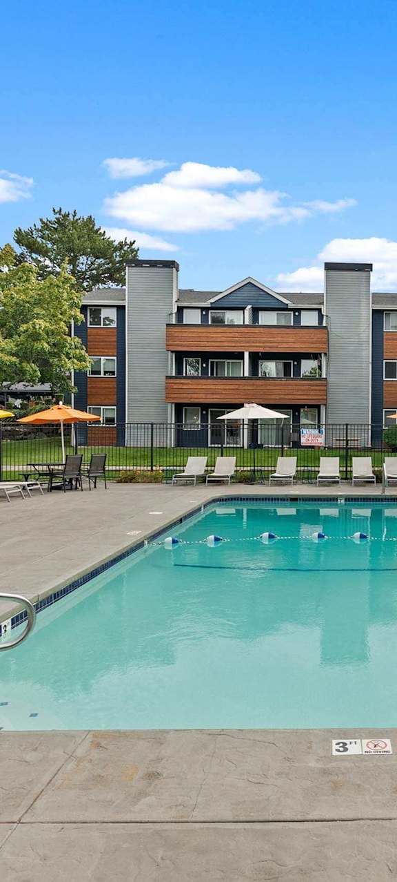 A large outdoor swimming pool with a concrete floor and a metal fence surrounding it.