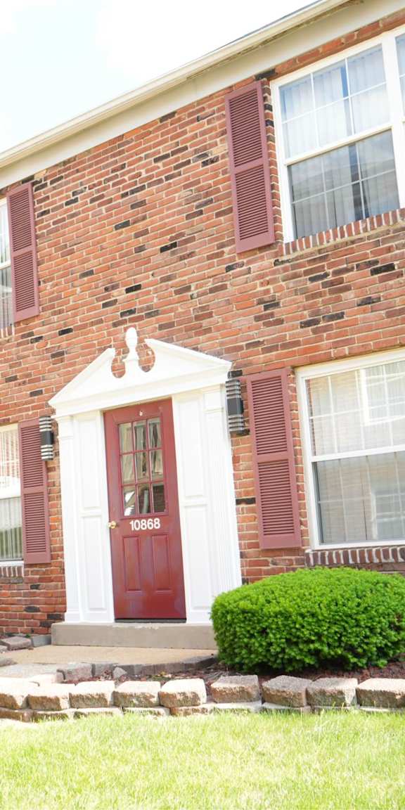 A red brick house with a white door and windows.