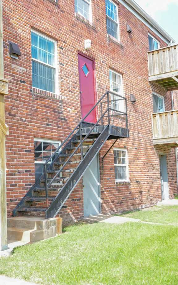 A red brick building with a wooden balcony and stairs.