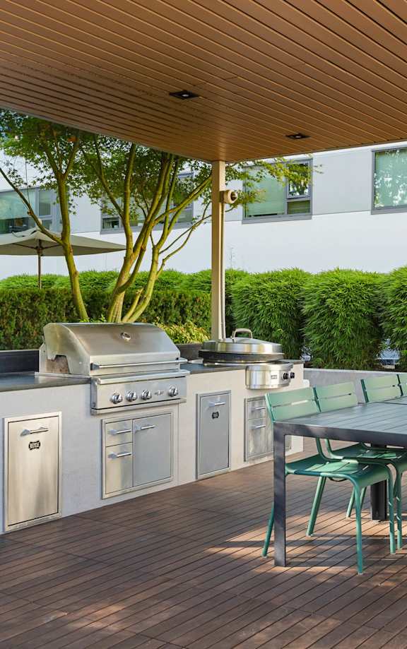 the outdoor kitchen has stainless steel appliances and a table with chairs