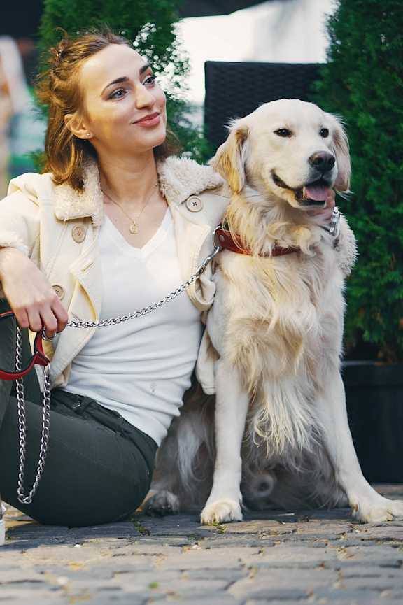 A woman is sitting on the ground with her dog. at The Sully, Chantilly