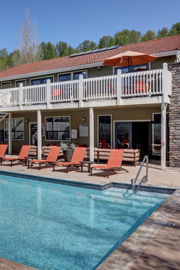 a swimming pool with orange chairs in front of a house at 2000 Lake Washington Apartments, Renton, WA, 98056