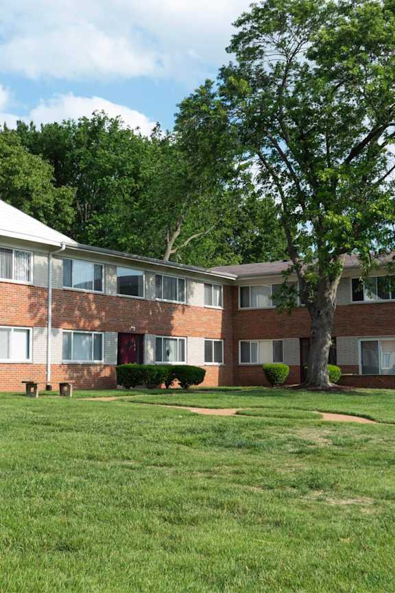 A large grassy area in front of a building with a tree.