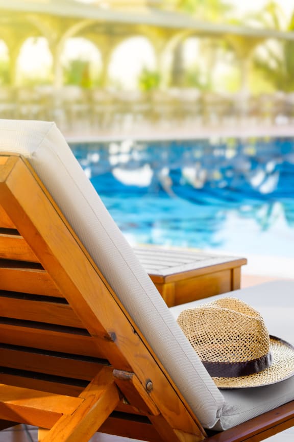 a hat is sitting on a beach chair next to a pool