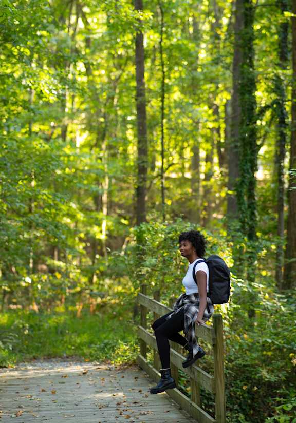 a man with a backpack walking on a wooden bridge in the woods at 111 Cosburn, Ontario
