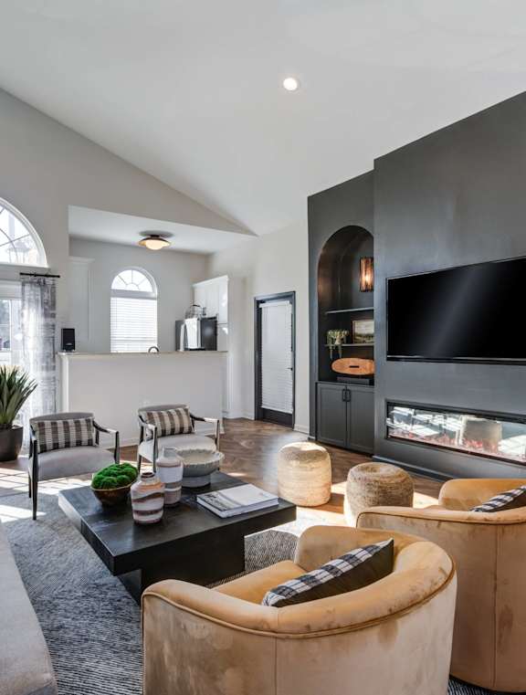 A modern living room with a grey sofa, a black coffee table, and a large window.