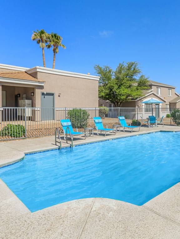 A swimming pool with blue water and lounge chairs.