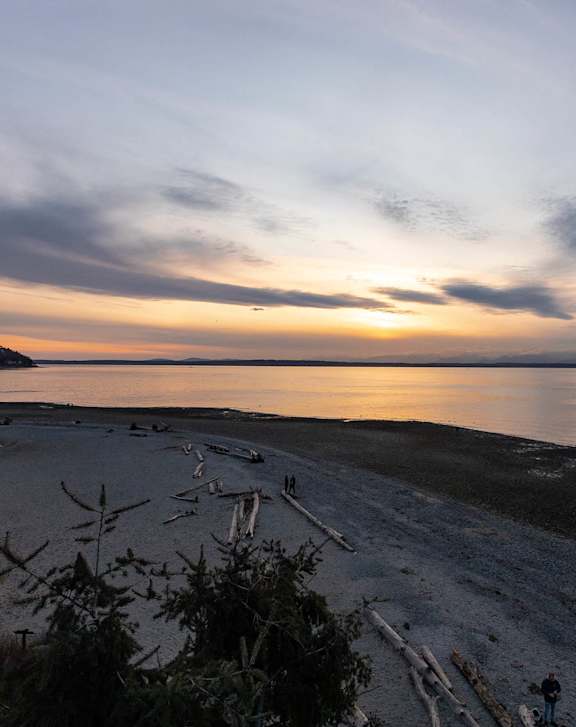 A beach at sunset with a person standing on the shore.