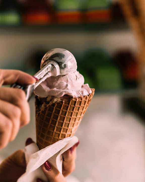 a person holding a cone of pink ice cream with a spoon at Willow Hill Apartments, Illinois, 60458