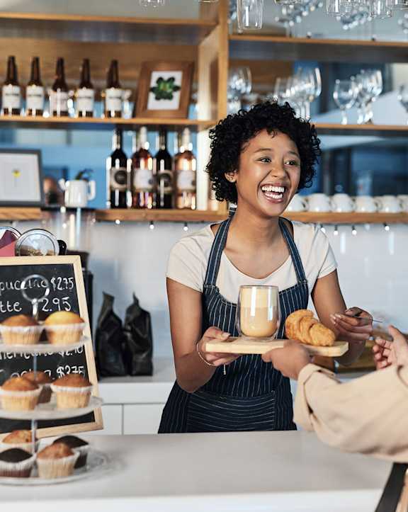 a barista handing a tray with coffee and pastry at Sunset Winds in Henderson, NV