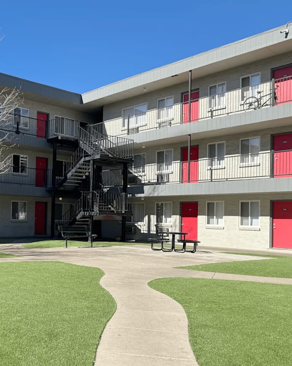 A view of a courtyard with a tree, benches and apartment buildings.