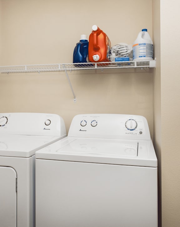 Two white washing machines in a laundry room.