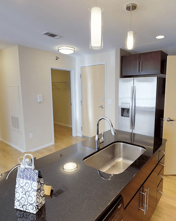 A kitchen with a black counter top and a white bag on it.