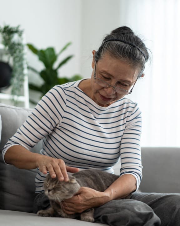 a woman petting her cat on a couch at Kirby Terrace Senior Apts, Hemet, 92545