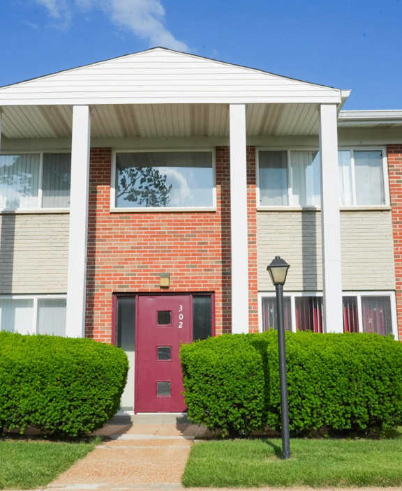 A red door is on the front of a brick building.