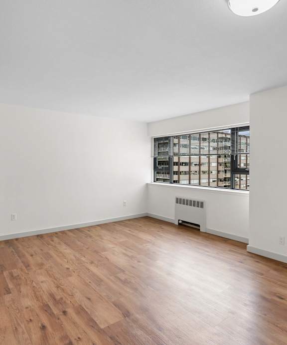 an empty living room with wood floors and a window