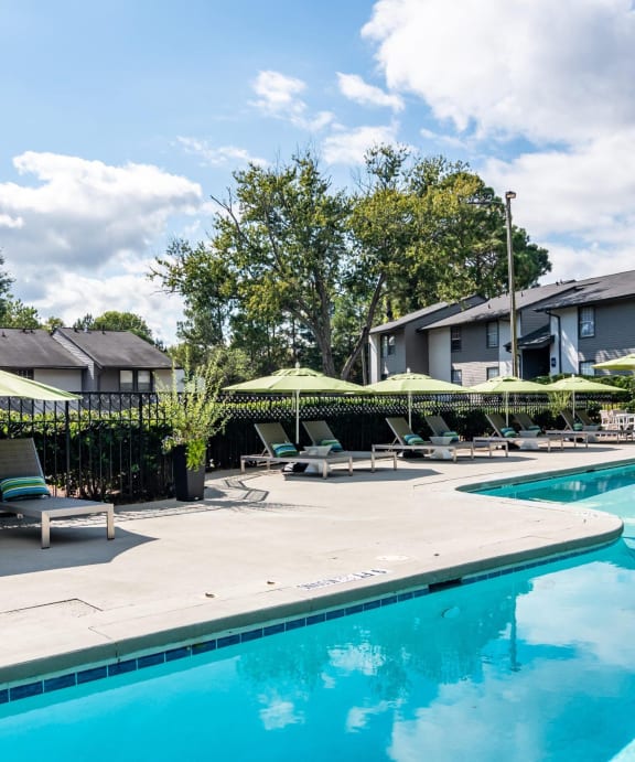 a swimming pool with lounge chairs and umbrellas next to a building at Glen Hollow, Decatur